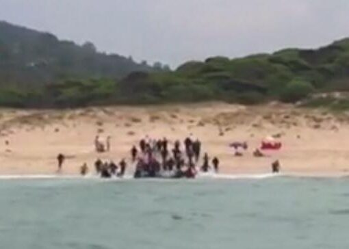 Zeci de migranți debarcă pe o plajă din Spania și apoi o iau la goană, sub privirile uimite ale turiștilor